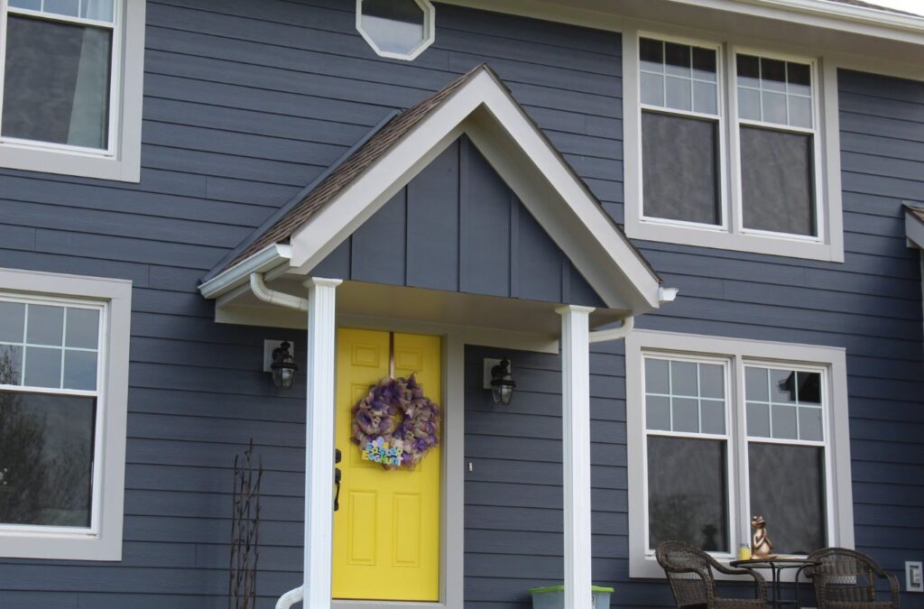 A Smart Exteriors crew member expertly installing vinyl siding in Peculiar, MO, using professional tools and craftsmanship.
